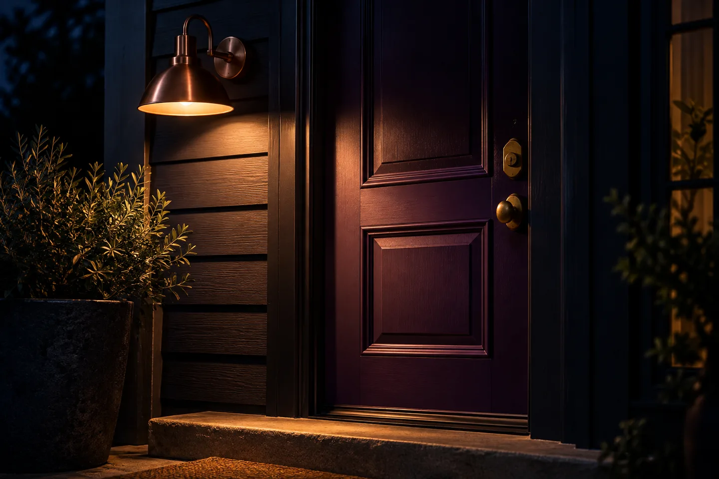 Copper wall light illuminating a violet entry door and lock at night
