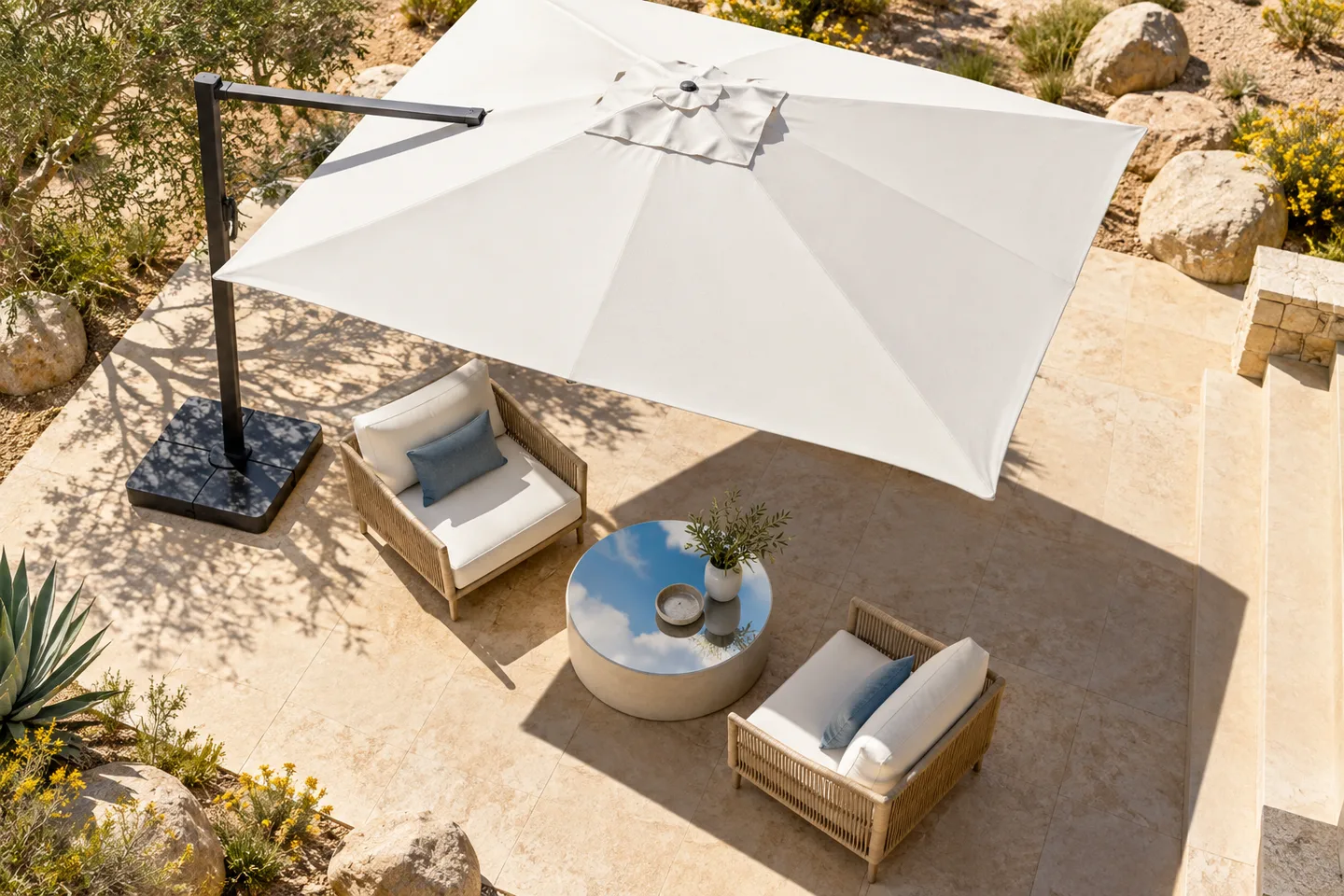 High-angle view of a white umbrella shading seating on a pale desert patio